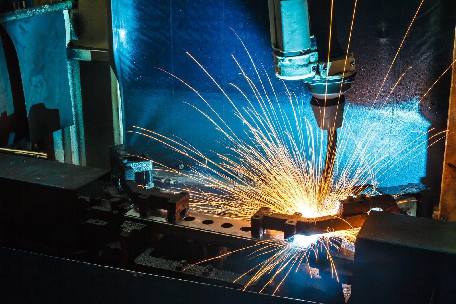 Manufacturing Web Design Robotic welding arm producing sparks on a factory line